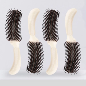 Detailed view of four cream-colored S-shaped hairbrushes with stiff dark brown bristles