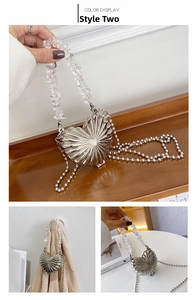 Macro shot of silver heart-shaped metal bag with beaded handle and fine radial textures