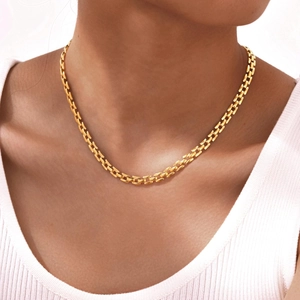 Elegant gold stainless steel watch-strap link necklace worn on a model over a white sweater