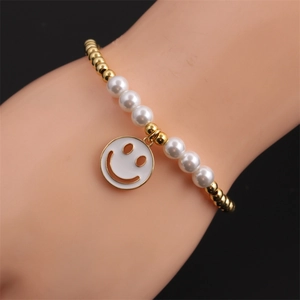 Détail du bracelet de perles dorées et de perles avec un pendentif smiley classique