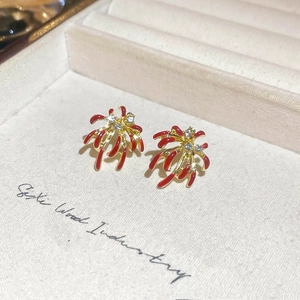 Vue macro de boucles d'oreilles feu d'artifice dorées, émail rouge et zircons