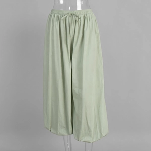 Detail of light green cotton lantern pants with elastic drawstring waist and loose fit