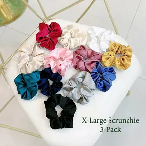 Oversized satin silk hair scrunchies set in multiple colors on a soft white surface