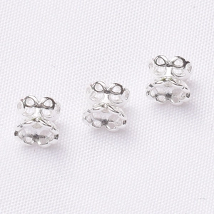 Macro detail of three silver hollow metal earring backs on white textured background