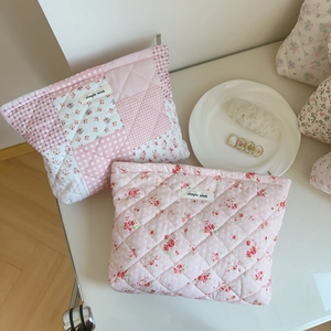 Détail du tissu en coton matelassé à fleurs roses et étiquette sur la trousse de toilette