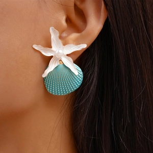 Macro detail of seaside style starfish and shell stud earrings with pearls on model