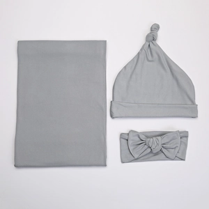 Close-up of soft grey knit baby swaddle set including a knotted hat and bow headband