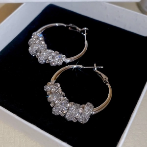 Macro shot of silver circular earrings with pave-set rhinestones in a black jewelry box