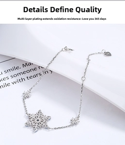 Detail of 925 sterling silver snowflake bracelet with blue crystals and a heart pendant