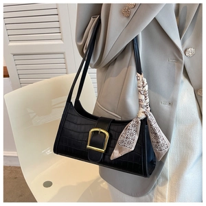 Detail of black crocodile pattern PU leather shoulder bag with gold D-buckle and silk scarf