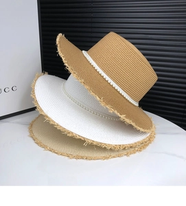 Close-up of stacked straw sun hats with pearl bead trim and frayed edge details