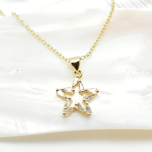 Macro shot of gold star pendant with cubic zirconia on white shell background