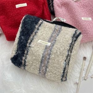 Platte weergave van kleurrijke boucle make-uptassen met ritssluiting op wit imitatiebont