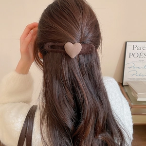 Macro shot of brown heart plush hair clip styled on a woman's bun hairstyle