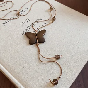Collier vintage avec pendentif papillon en bois et perles de cristal sur un vieux livre