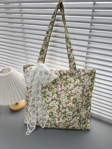 Detail view of floral canvas tote bag with white lace bow on a light desk