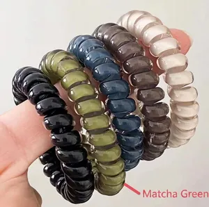 Close-up of flexible spiral phone cord hair ties in assorted matte neutral colors