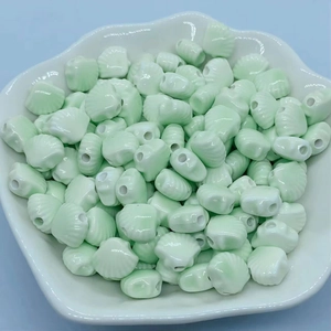 Close-up of light green shell-shaped ceramic beads for DIY jewelry making and crafts