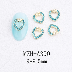 Détail de bijoux d'ongles en forme de cœur avec nœud doré et strass bleu clair