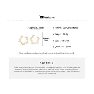 Detailed view of hollow floral hoop earrings with sparkling rhinestones in gold finish