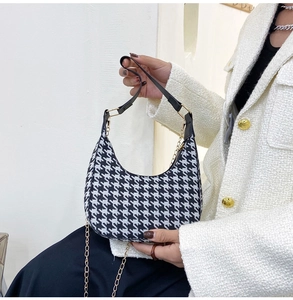 Detail of houndstooth half-moon bag with gold chain and black strap on model