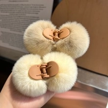 Close-up of fluffy beige rabbit fur hair clips with plush texture and side snap grips