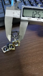 Detailed measurement of metal earring size using a digital caliper showing 1.25 units