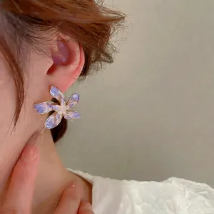 Boucles d'oreilles fleurs au dégradé violet et bordure dorée portées par un mannequin