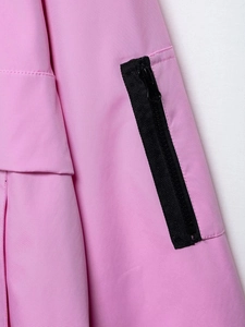 Detail view of pink jacket fabric showing a black zipper pocket and twill texture