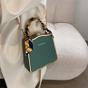 Elegant dark green box bag with gold metal frame and silk scarf wrapped handle