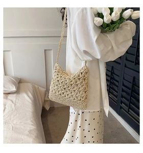 Close-up of beige crochet crossbody bag with 3D floral patterns for summer beach vacation