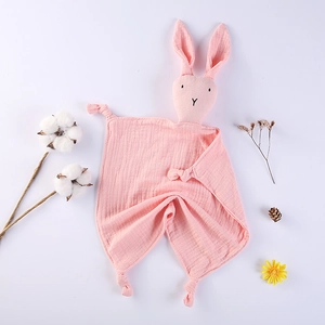 Détail d'un doudou pour bébé en gaze de coton rose avec tête de lapin et coins noués