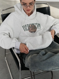 Detail of grey oversized hoodie featuring green HEDONISM print and streetwear aesthetics
