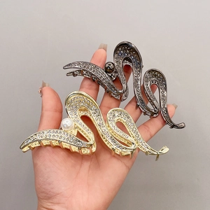 Close-up of wavy gold and silver metal hair claws with sparkling rhinestones and pearls