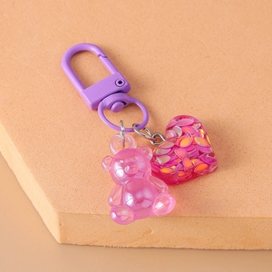 Close-up of a pink resin bear and heart charm with a purple metal lobster clasp