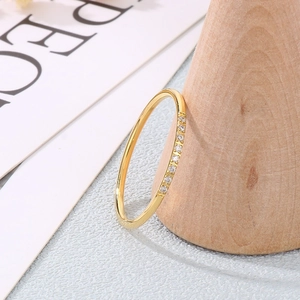 Close-up of minimalist gold ring with seven sparkling zircons on a wooden stand