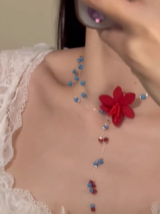 Detailansicht der handgefertigten Blumenkette mit roten Blüten und blauen Perlen am Modell