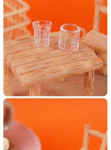 Miniature dollhouse scene with transparent wine glass and mug on a tiny wooden table