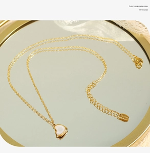Vue détaillée du collier à pendentif cœur en nacre avec étiquette gravée S.Steel