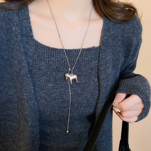 Silver horse pendant necklace with brushed metal finish worn over a grey cardigan