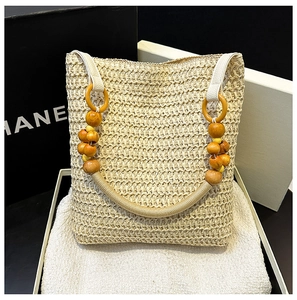 Detailed view of woven straw tote bag with vibrant orange and yellow wooden bead handles