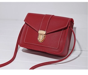 Detail of red small square bag featuring white contrast stitching and gold metal clasp