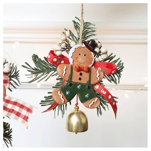 Detail of gingerbread man Christmas ornament with red bow, green overalls and gold bell