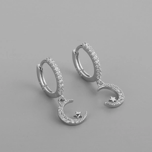 Macro shot of silver S925 star and moon earrings with white zircon on grey background