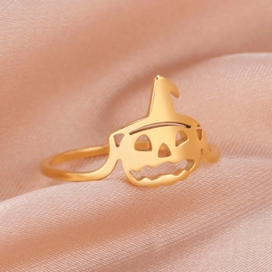 Macro shot of gold stainless steel Halloween pumpkin ring on pink silk fabric