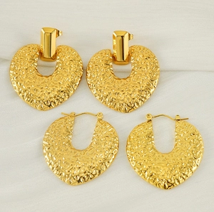 Détail des boucles d'oreilles cœur dorées avec une texture en métal martelé unique