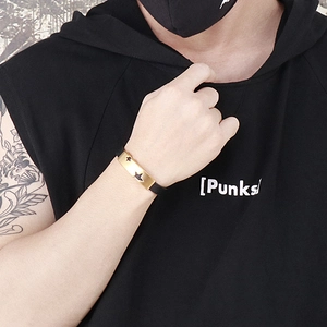 Detail of a punk leather bracelet with a gold metal star cutout on a tattooed wrist