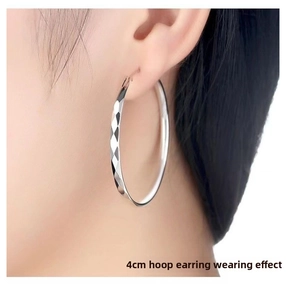Detailed view of 4cm silver hoop earring with diamond-cut texture on female model
