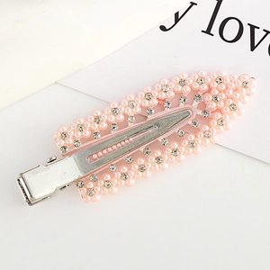 Detailed macro view of a pink flower hair clip featuring faux pearls and rhinestones