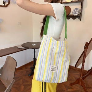 Détail du sac cabas en toile rayée avec texture plissée et bandoulière verte contrastée